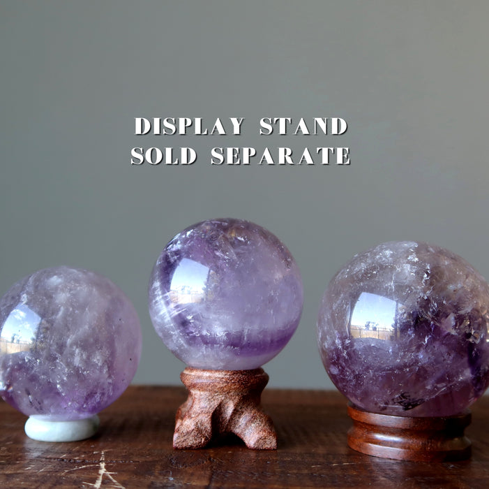three purple amethyst spheres on display stands
