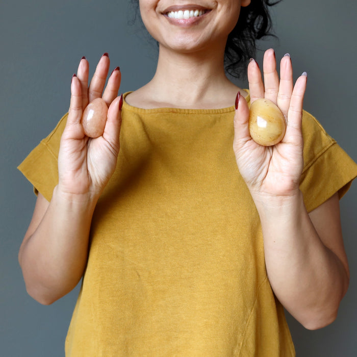 female holding one yellow aventurine egg in each palm