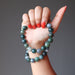 hand holding and wearing green and white moss agate round beaded stretch bracelets