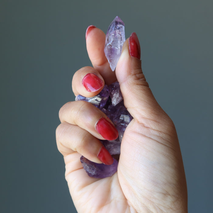 hand holding raw amethyst crystal points