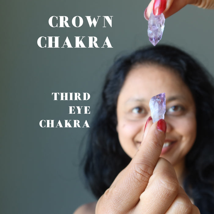 hand holding amethyst points at crown and third eye chakras