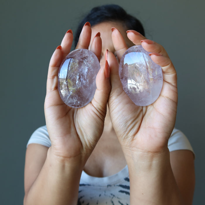 sheila of satin crystals holding two translucent purple oval polished palm stones in her palms