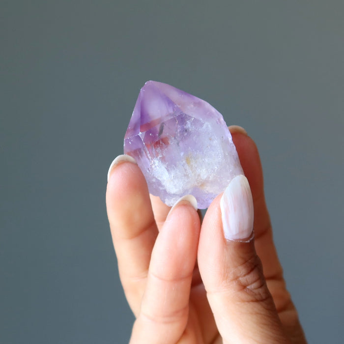 fingers holding a raw purple amethyst points