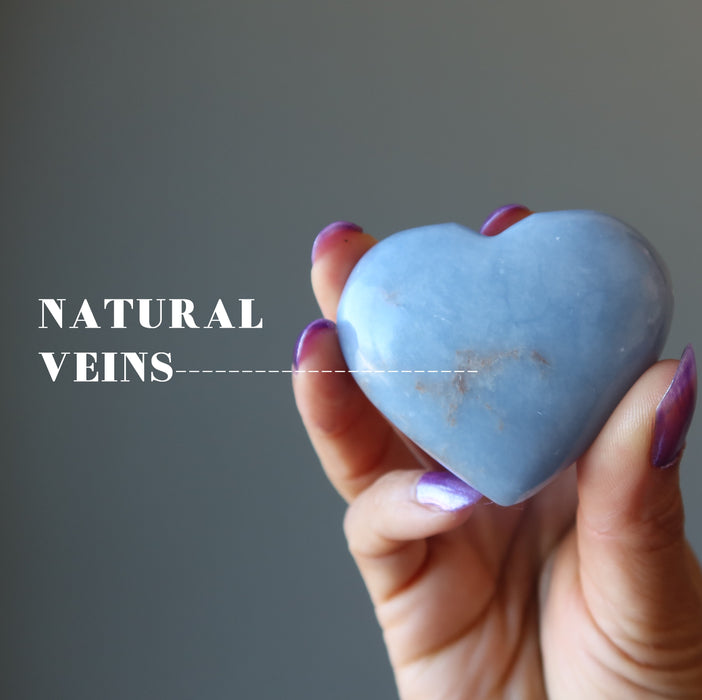 hand holding angelite heart showing natural brown veins