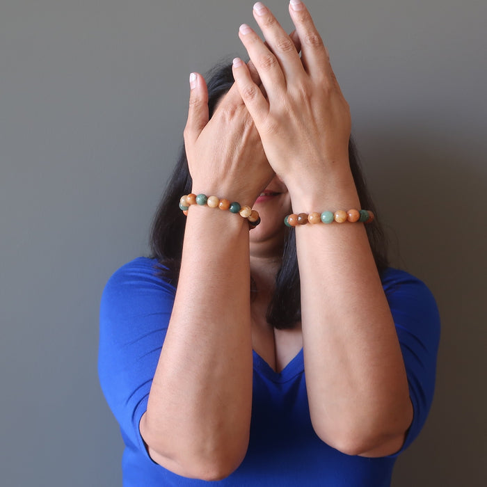 jaren of satin crystals with hands in front of her face wearing multi colored aventurine stretch bracelets