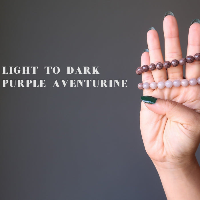 hand holding up two purple aventurine bracelets to show the color variation from light to dark