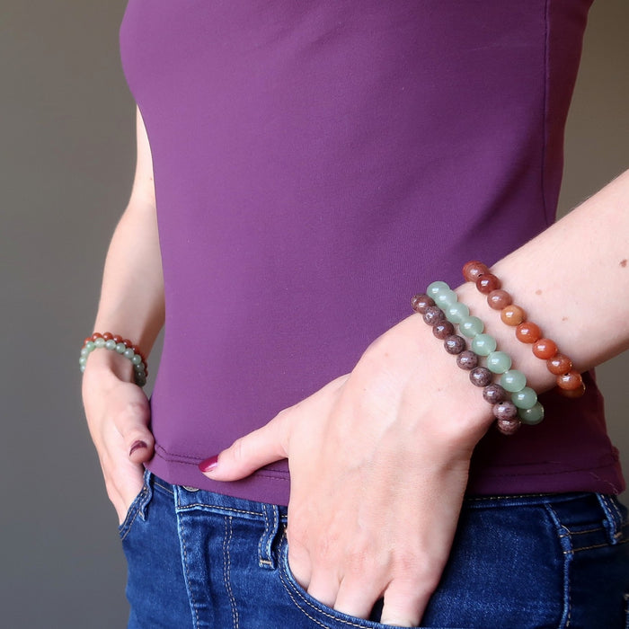 female hands in pocket modeling red, purple, green aventurine bracelet sets