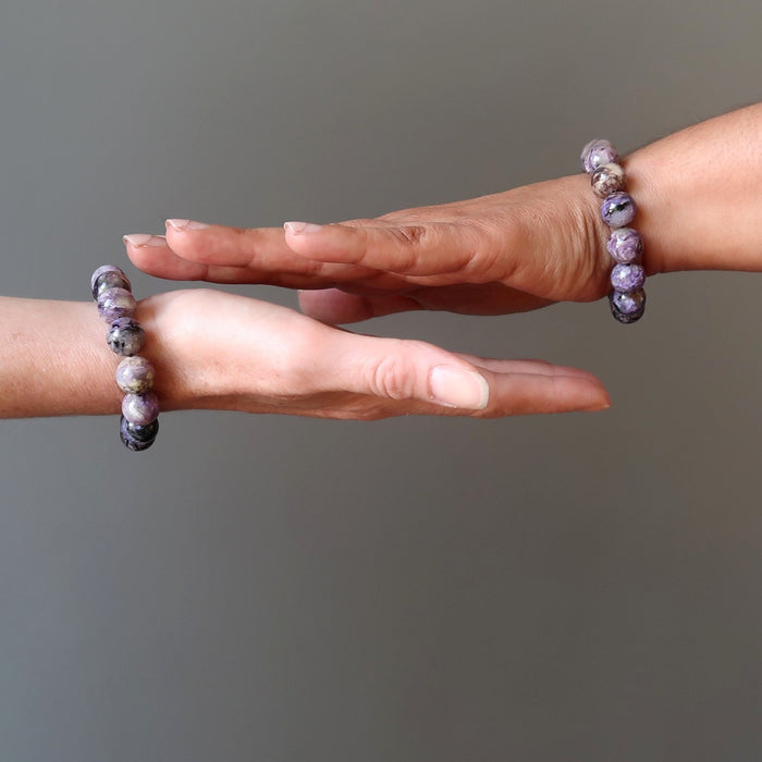 two female hands modeling purple charoite stretch bracelets