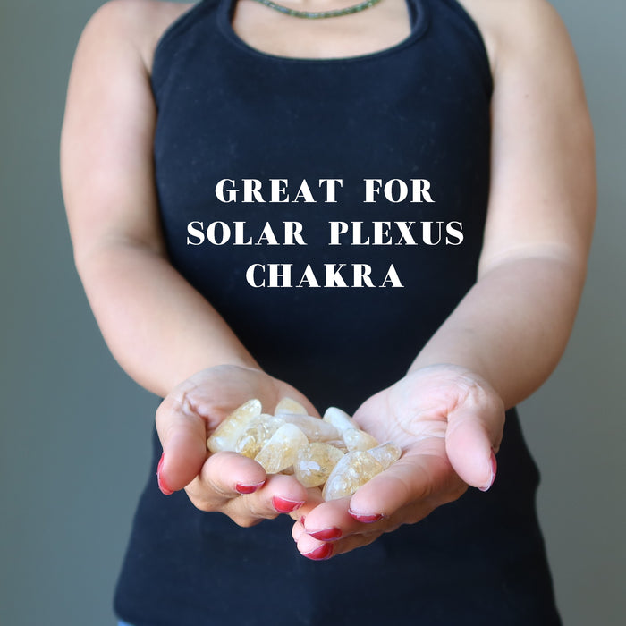 hands holding translucent yellow citrine tumbled stone set for the solar plexus chakra