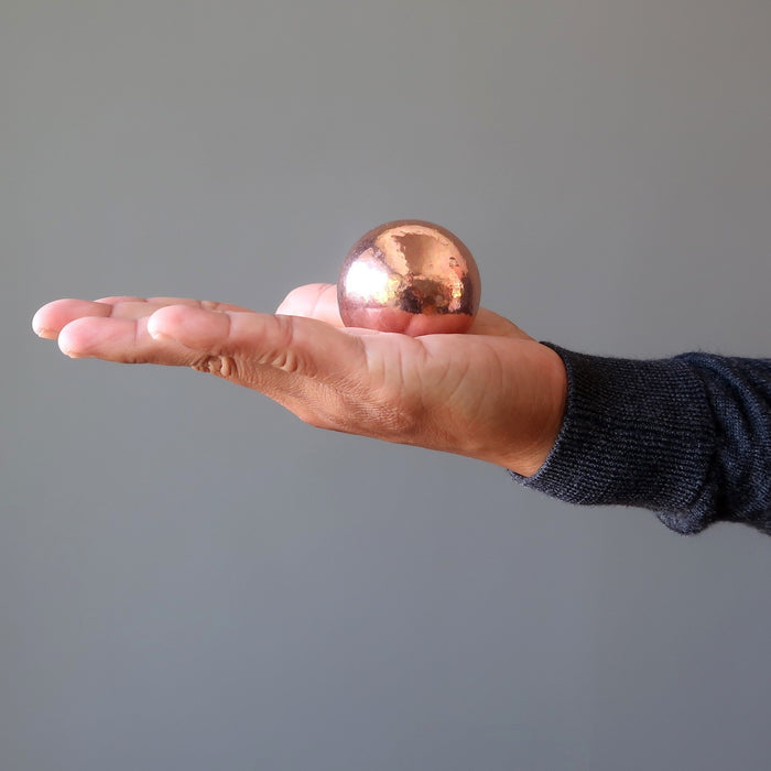 hand holding a copper sphere