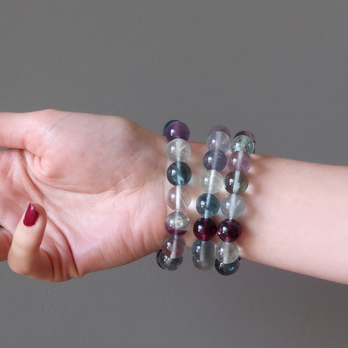 hand wearing 3 rainbow fluorite beaded stretch bracelets