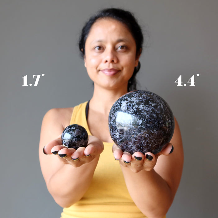 sheila of satin crystals holding 1.7" and 4.4" Indigo Merlinite Gabbro Spheres