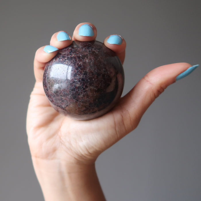 hand holding a red garnet sphere