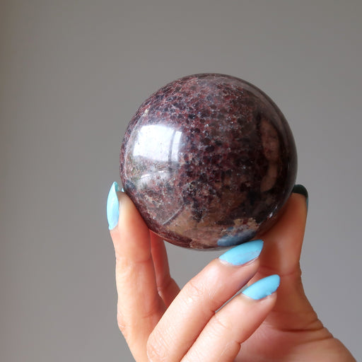 hand holding a red garnet sphere
