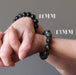 hands wearing an 11mm and 13mm hawks eye beaded bracelet