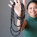 sheila of satin crystals holding up 3 black jet stone beaded necklaces