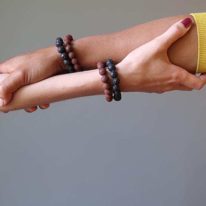 man and woman's arm clasping each other both wearing red and black lava bracelet sets