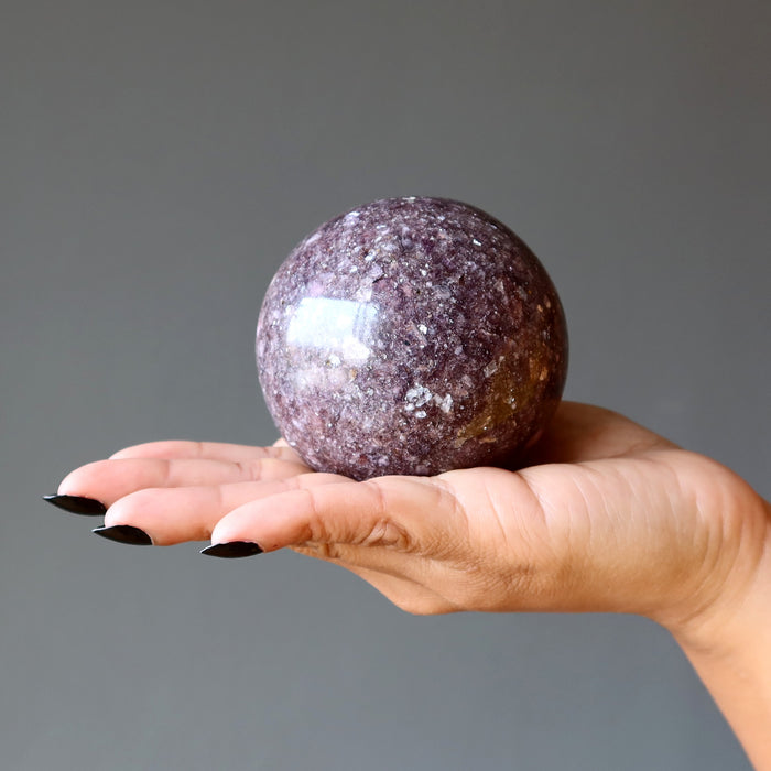 purple lepidolite sphere on palm of hand