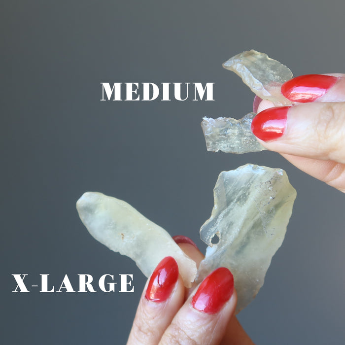 hands holding two pairs of libyan desert glass to show difference between medium and x-large sizes