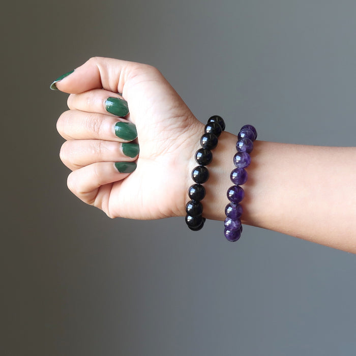 female hand wearing black tourmaline and amethyst bracelet set