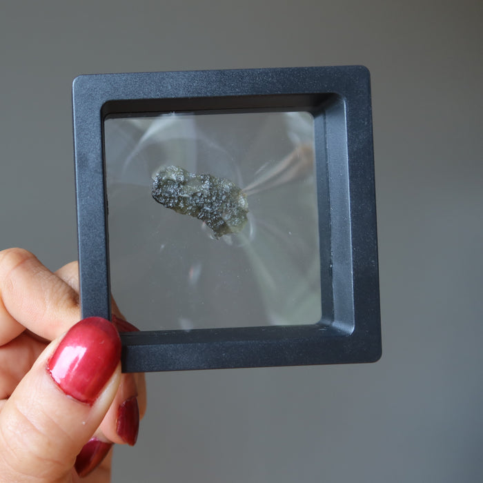 hand holding  moldavite in a display case