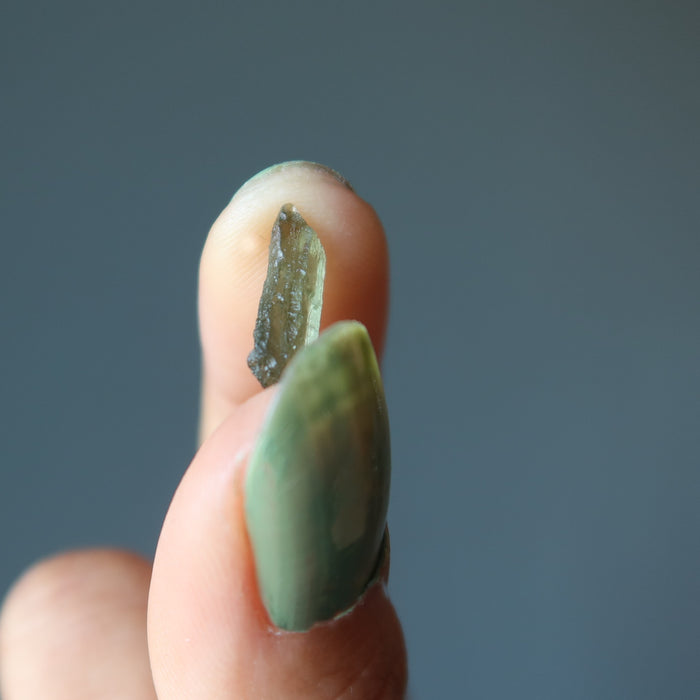 hand holding rough green moldavite gemstone