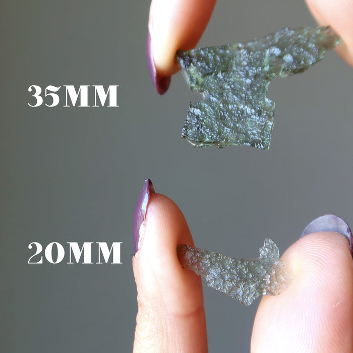 hands holding two moldavite raw pieces