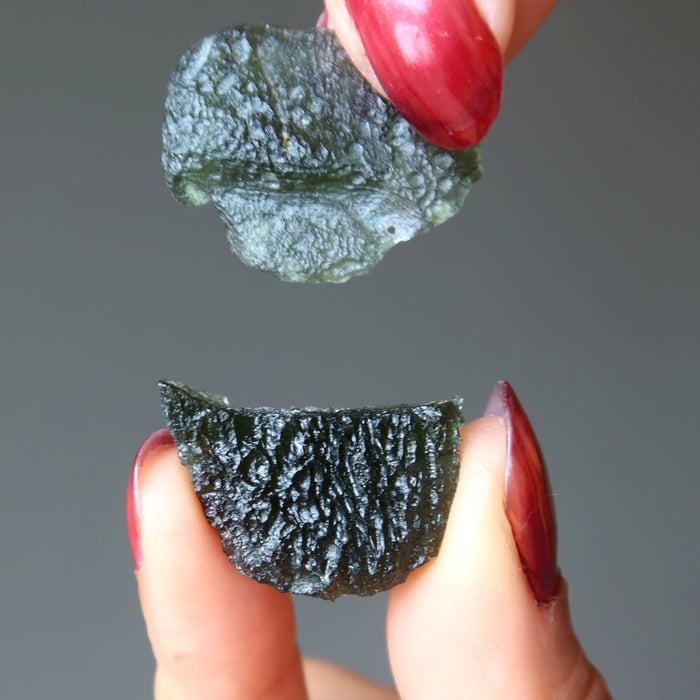hands holding two moldavite crystals