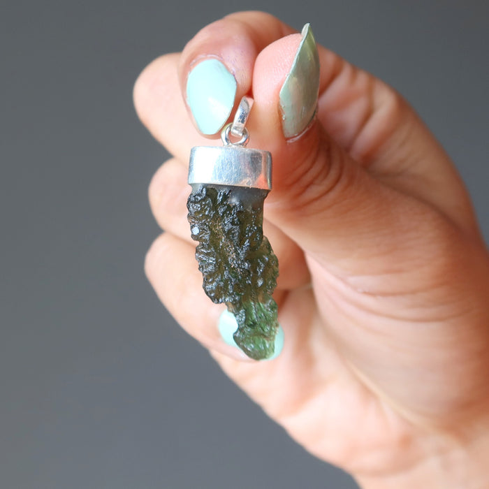hand holding raw green moldavite pendant