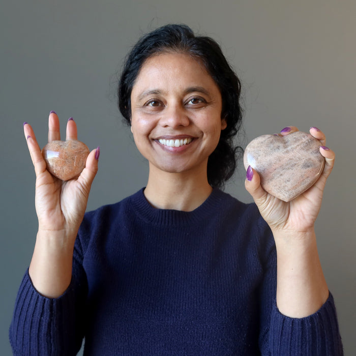 woman holding two moonstone hearts
