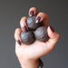 hand holding three brown moqui marble stones