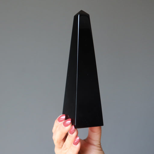 hand holding black obsidian obelisk