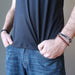 a gentleman models the three piece obsidian bracelet set on his arms while placing hands in jean pockets