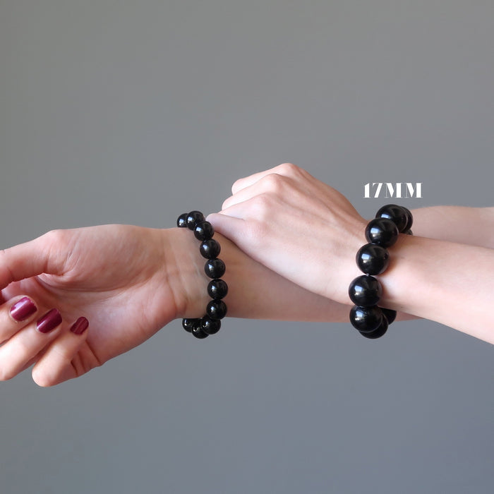 woman's two hands wearing rainbow obsidian beaded stretch bracelets
