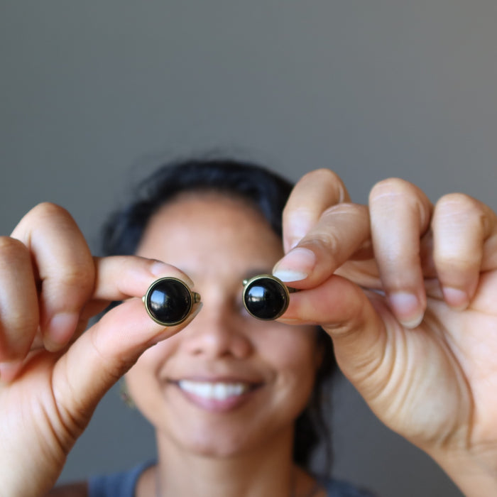 female holding black onyx cufflinks in front of her eyes