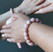 two people wearing pink opalite bracelets on their wrists