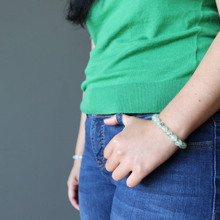 green prehnite crystal bracelet on the wrist of a lady holding her hands to her jean pocket