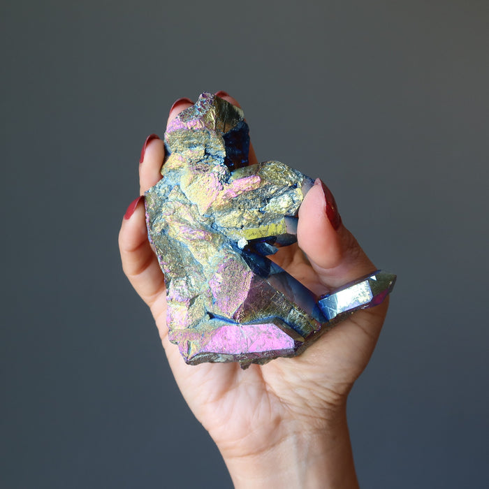hand holding raw rainbow aura titanium quartz cluster