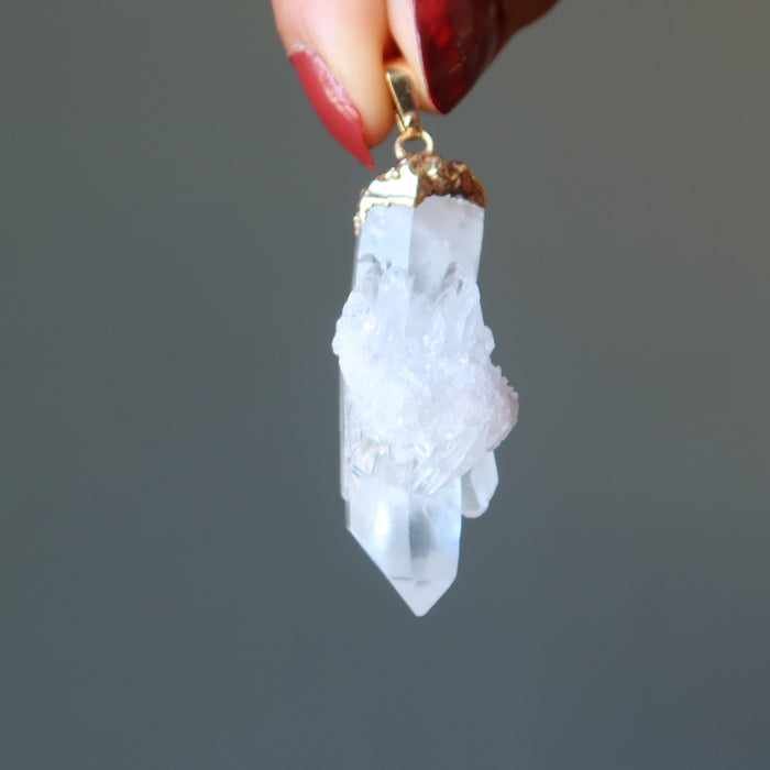 hand holding raw quartz cluster pendant in gold electroplating