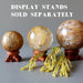 three golden quartz spheres on wood display stands and a sprig of pine 