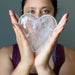 sheila of satin crystals holding a big Clear Quartz Heart with both hands in front of her face