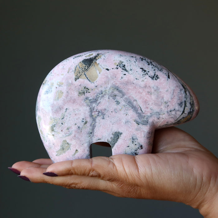 woman holding large rhodonite bear crystal on hand