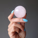 hand holding pink rose quartz crystal ball