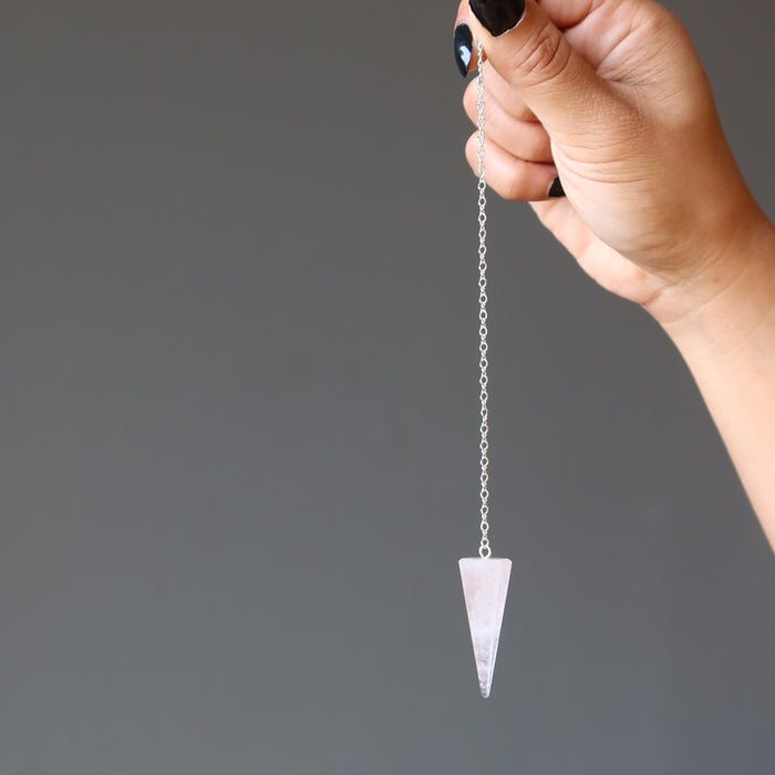 hand holding rose quartz pendulum