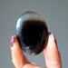 hand holding a black and brown sardonyx oval polished stone