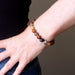 brown and red sardonyx bracelet on the wrist of a lady who has her hand on her hips