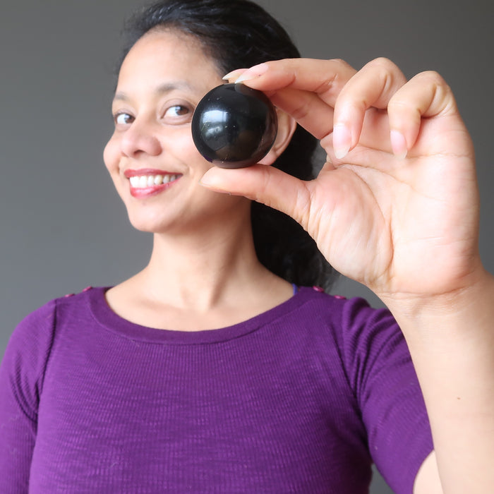 sheila of satin crystals holding up a shungite sphere