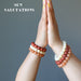 hands in prayer for sun salutation wearing yellow calcite, orange aventurine, red jasper stretch bracelet sets
