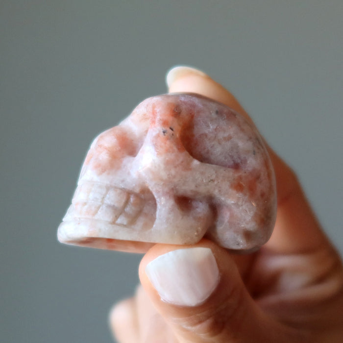 Sunstone Skull between two finger tips