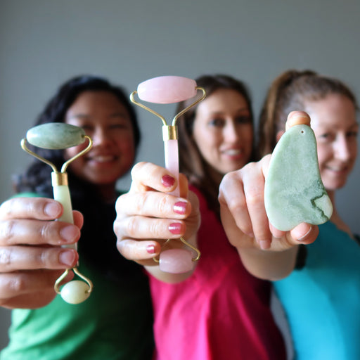 jessica and holly of satin crystals holding jade and rose quartz facial roller wands and jamie holding a jade scraper
